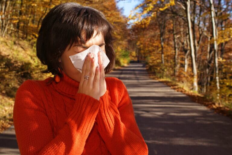 Woman outside sneezing into a tissue