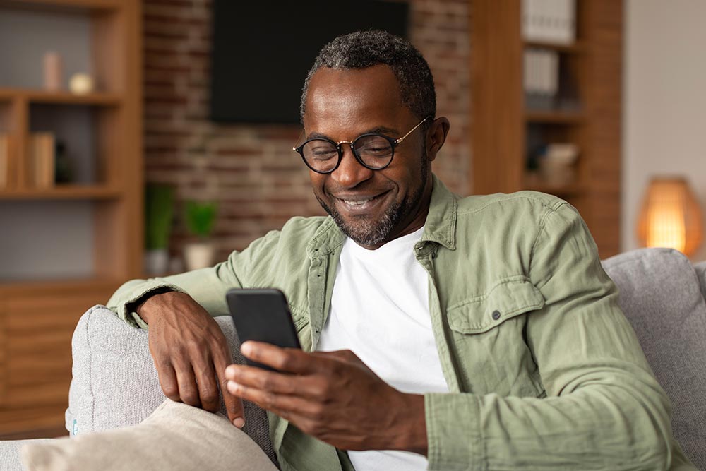 Senior man looking at his phone at home